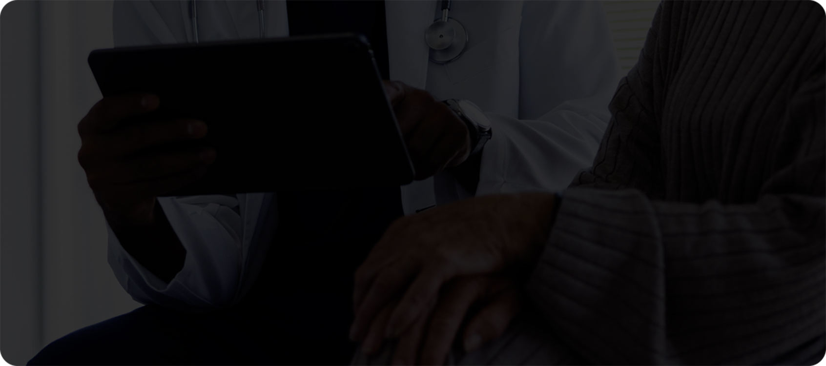 un patient et un professionnel de la santé assis l’un à côté de l’autre et regardant un iPad ou un appareil semblable